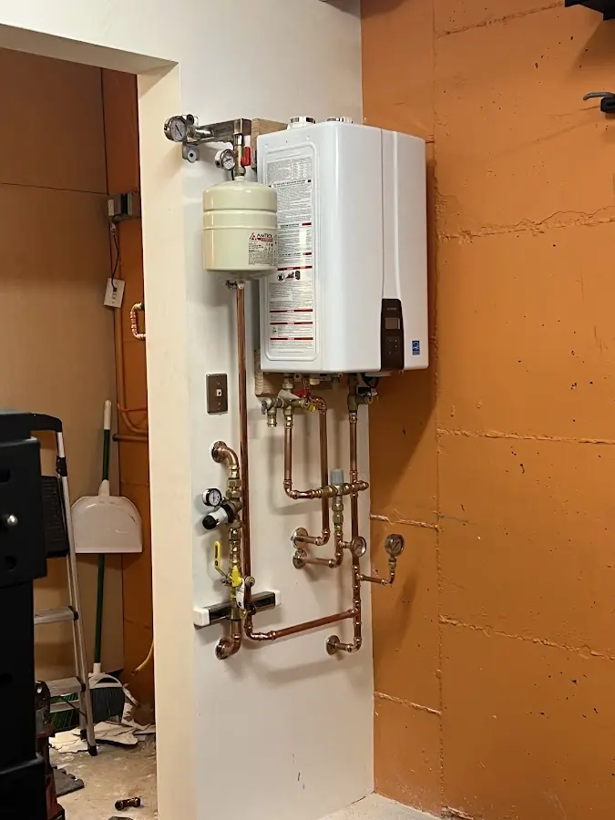 Plumbing technician inspecting water heater connections in Wall